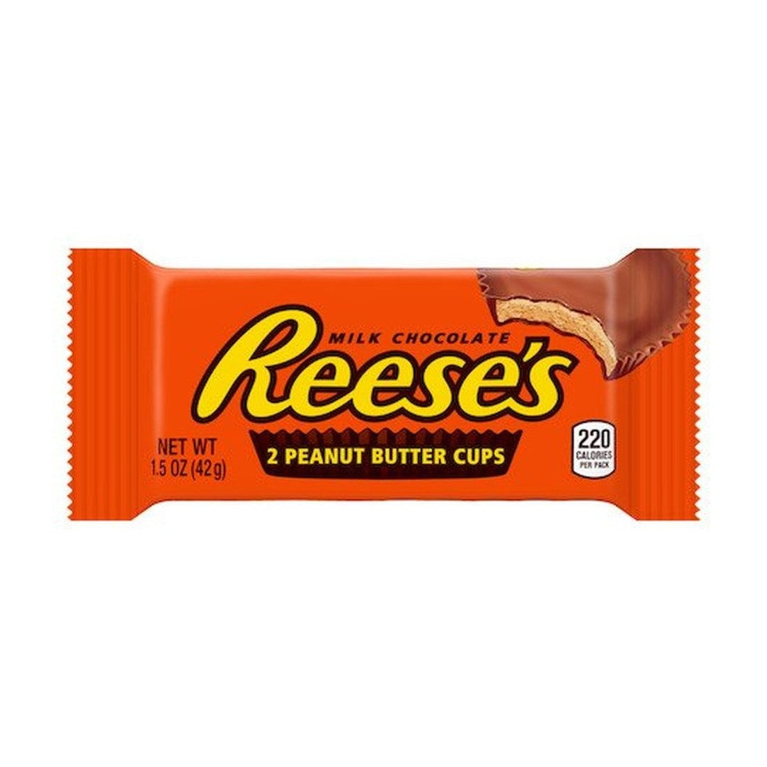 Un emballage orange sur fond blanc avec écrit « Reese’s » au centre et au milieu, au-dessus à droite il y a un chocolat en cup qui est croqué et on y voit une pâte brune claire