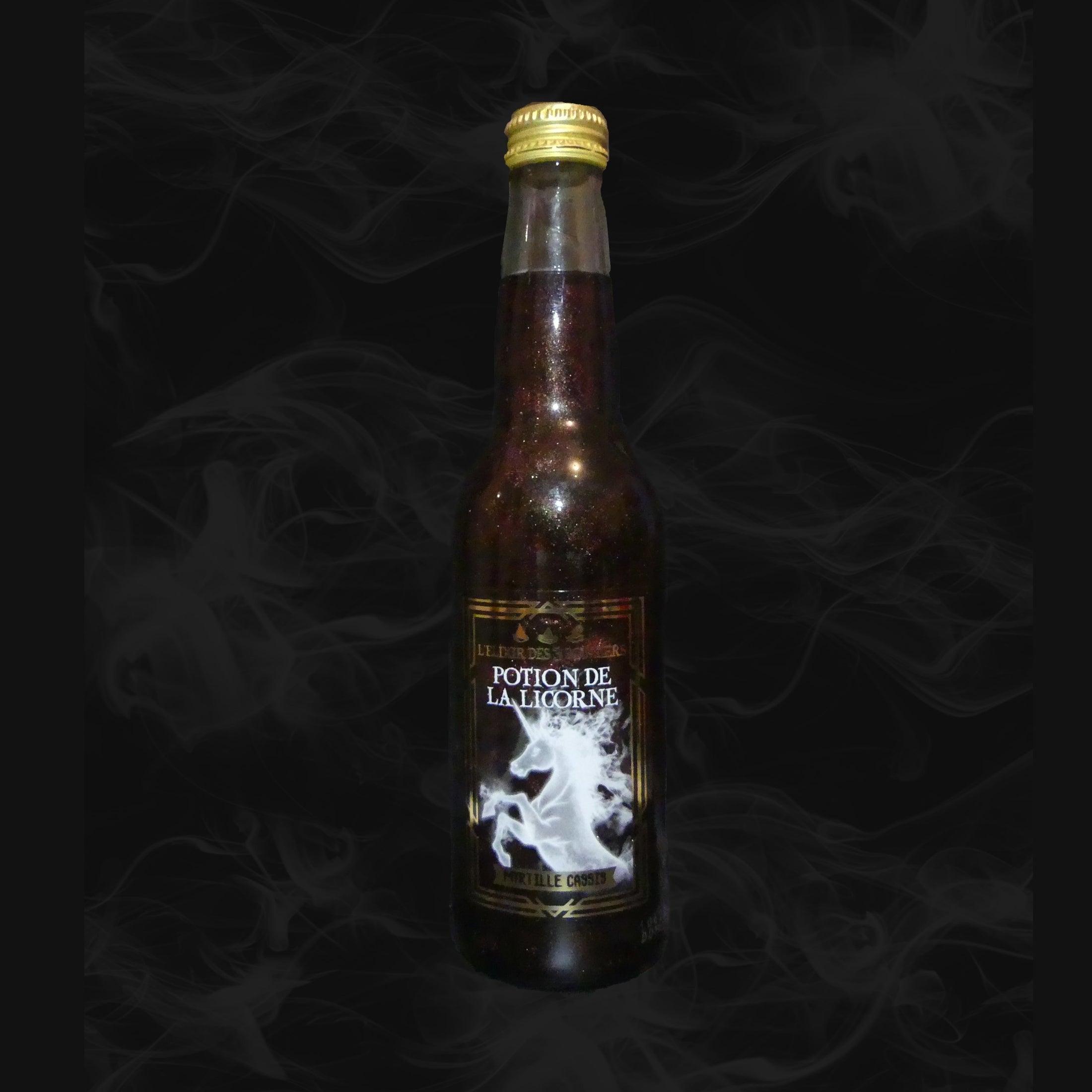 Une bouteille transparente avec une boisson pailletée noire et sur l’étiquette une licorne blanche. Le tout sur fond noir avec de la fumée