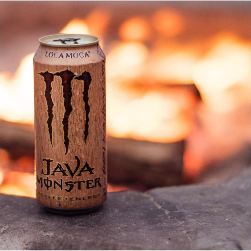 Une grande canette brune avec au centre un grand M marron et derrière il y a un feu de bois