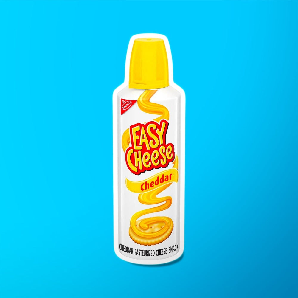 Une bouteille blanche sur fond bleu avec un capuchon jaune, sur l’emballage il y a un crackers rond avec du fromage orange qui tombe d’en haut en zigzag 