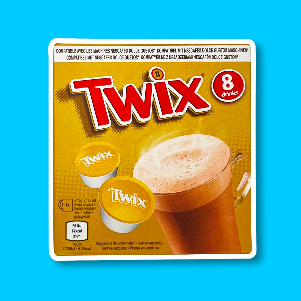 Un carton doré sur fond bleu avec une grande tasse transparente avec du chocolat chaud et à gauche 2 capsules blanches et jaunes