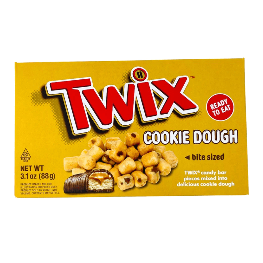 Un carton jaune sur fond blanc avec écrit en grand et en rouge « TWIX », en-dessous il y a des petits morceaux de pâtes de cookie et devant une moitié de Twix