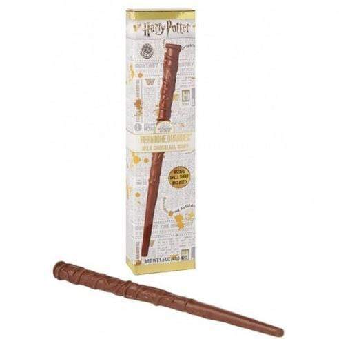 Un carton blanc sur fond blanc avec les motifs d’un journal et dessus la baguette magique d’Hermione en chocolat. Devant l’emballage, la baguette en chocolat