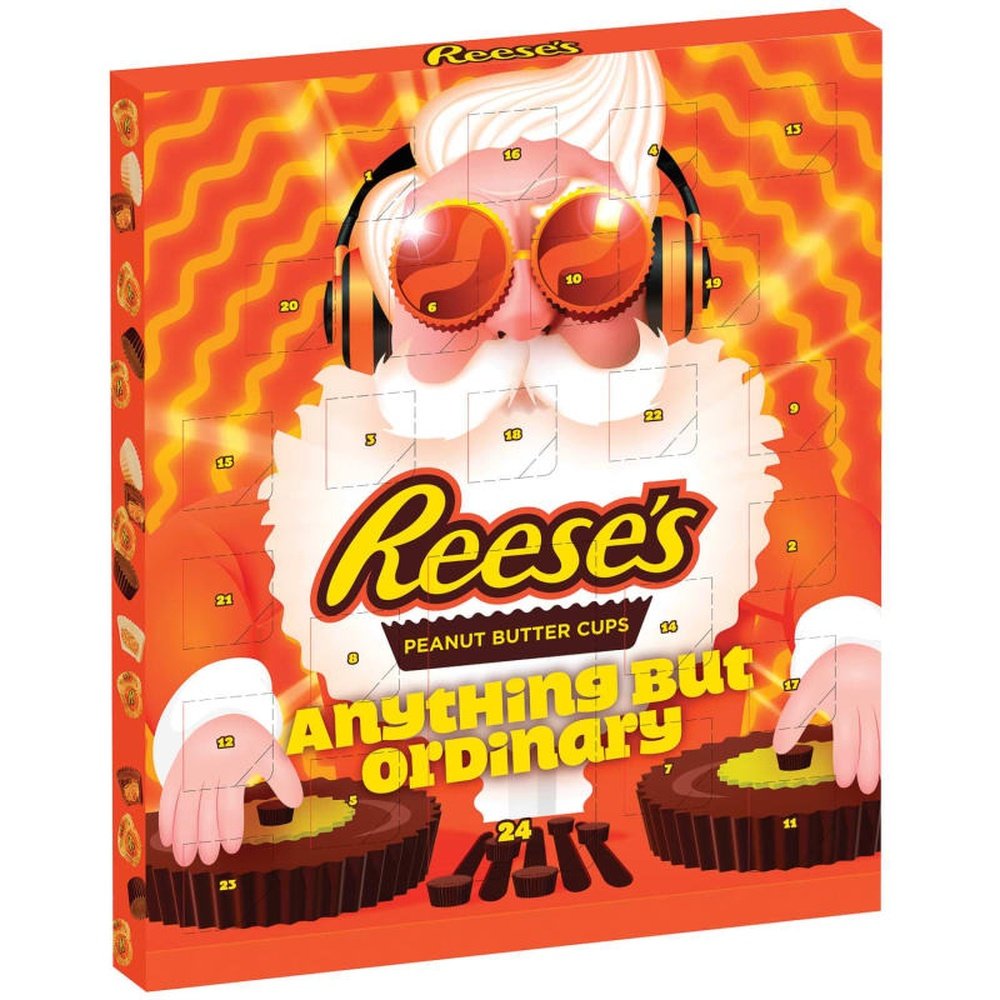 Un paquet orange sur fond blanc avec un père Noël à lunettes et avec un casque sur la tête, il mixe sur des platines en forme de Reese’s