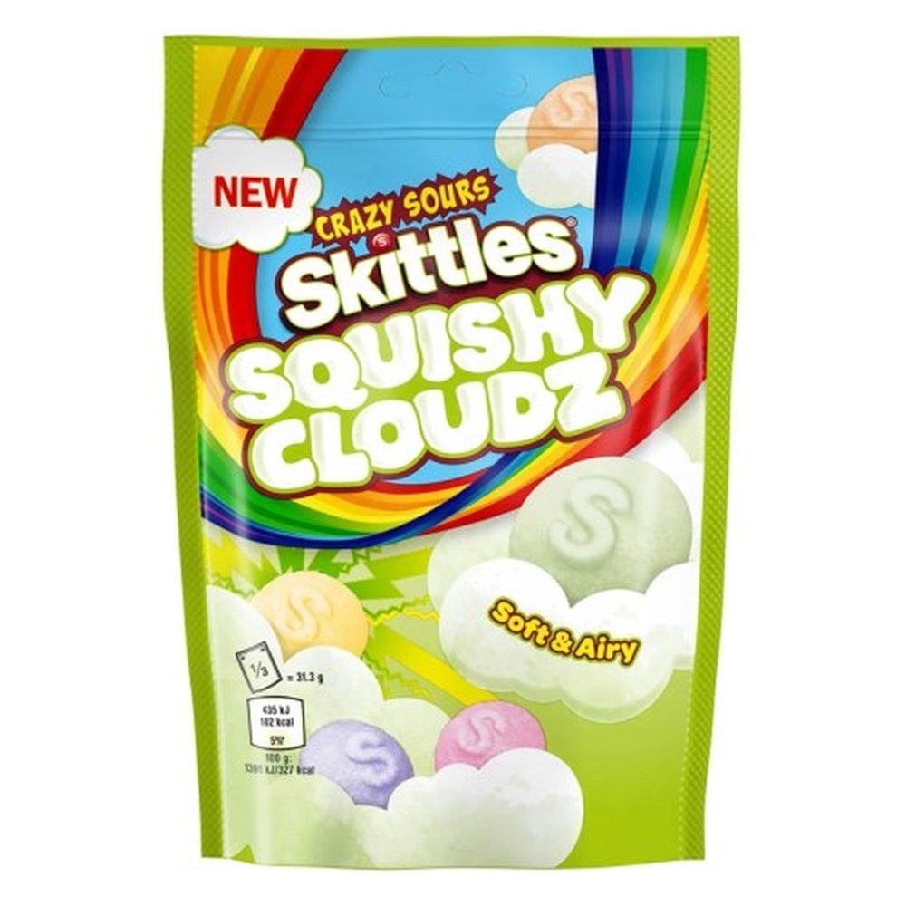 Un emballage vert sur fond blanc avec un arc-en-ciel et des Skittles colorés sur des nuages verts pâles